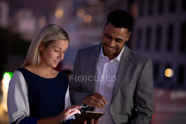 Diverse männliche und weibliche Kollegen arbeiten nachts mit Tablets und sprechen. spät arbeiten in einem modernen Büro. — Stockfoto