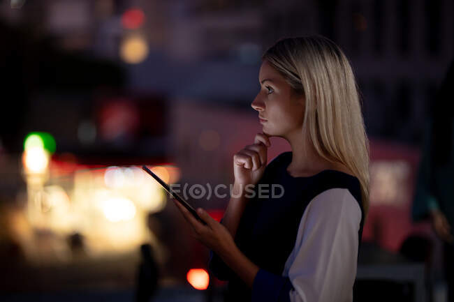 Кавказская деловая женщина работает по ночам с помощью смартфона. работать допоздна в современном офисе. — стоковое фото