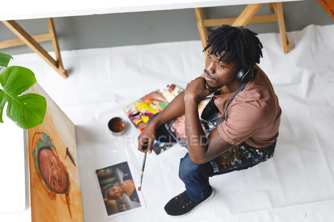 African american male painter at work painting portrait on canvas in art studio. creation and inspiration at an artists painting studio. — Stock Photo