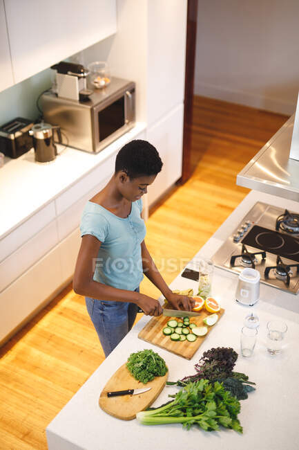 Afroamerikanerin in der Küche, die Gemüse und Obst hackt. häuslicher Lebensstil, Freizeit zu Hause genießen. — Stockfoto