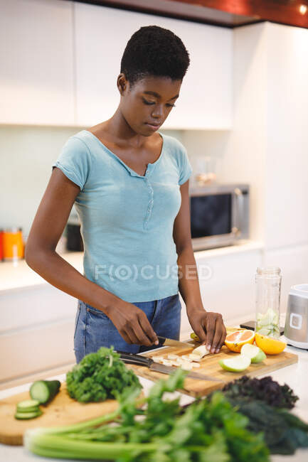 Африканська американка на кухні рубає овочі і фрукти. Домашнє життя, дозвілля вдома. — стокове фото