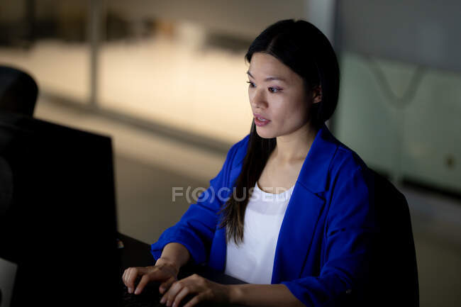 Donna d'affari asiatica che lavora di notte usando il computer. lavorare fino a tardi negli affari in un ufficio moderno. — Foto stock