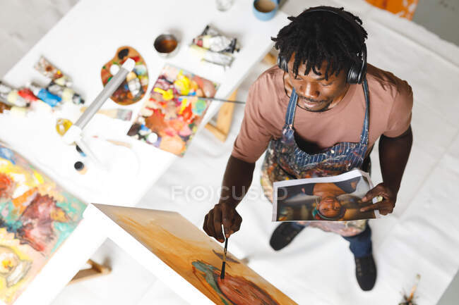 Африканский американский художник-мужчина за работой пишет портрет на холсте в художественной студии. создание и вдохновение в студии живописи художников. — стоковое фото
