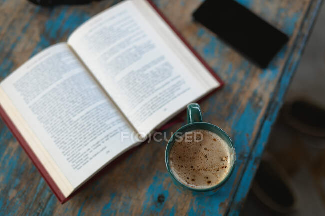 Abra el libro y la taza de café en la mesa. estilo de vida de jubilación, pasar tiempo solo en casa. - foto de stock