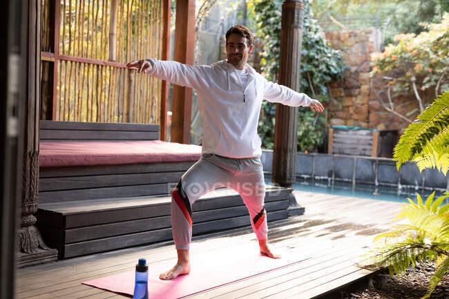 Kaukasischer Mann in Sportbekleidung und Yoga auf Yogamatte. Auszeit zu Hause. — Stockfoto