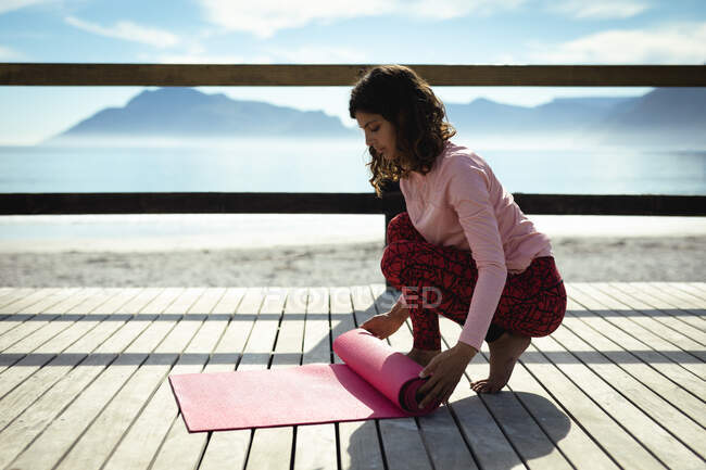 Змішана расова жінка практикує йогу в сонячний день на узбережжі. здоровий спосіб життя, насолоджуючись дозвіллям на відкритому повітрі . — стокове фото