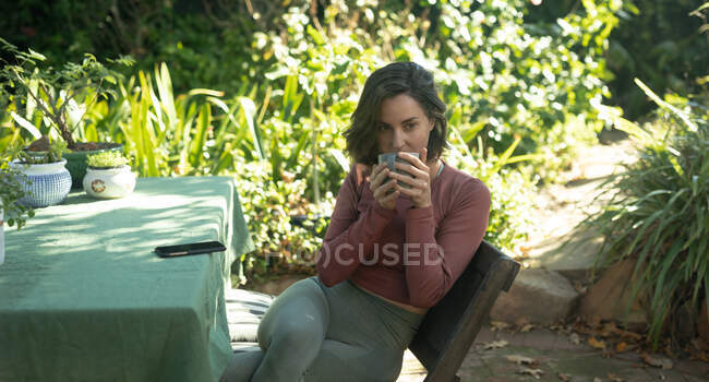 Mulher branca no jardim, sentada à mesa a beber café. estilo de vida doméstico, desfrutando de tempo de lazer em casa. — Fotografia de Stock