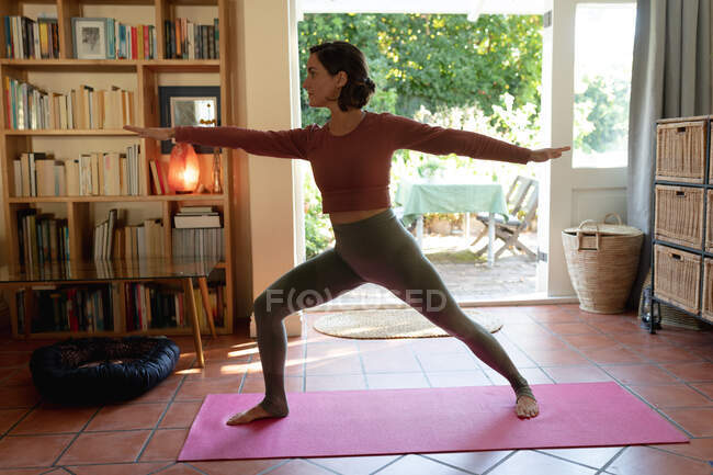 Mujer caucásica en sala de estar, practicando yoga, estiramiento. estilo de vida doméstico, disfrutando del tiempo libre en casa. - foto de stock