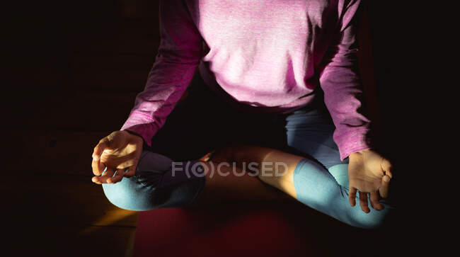 Mujer practicando yoga, sentada meditando en salón soleado. estilo de vida saludable, disfrutando del tiempo libre en casa. - foto de stock