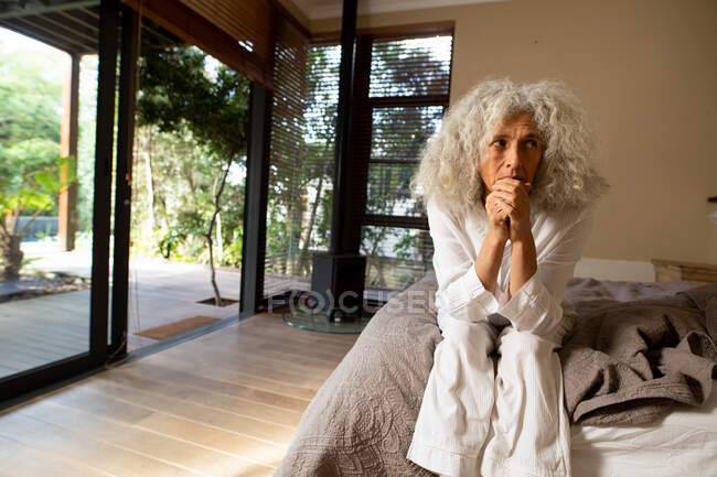 Nachdenkliche ältere kaukasische Frau, die auf dem Schlechten sitzt und denkt. Lebensstil im Ruhestand, Zeit allein zu Hause verbringen. — Stockfoto