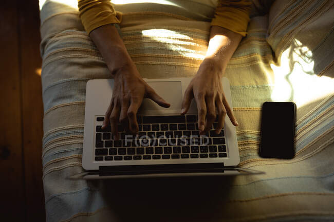 Femme couchée et utilisant un ordinateur portable dans le salon ensoleillé. mode de vie sain, profiter de loisirs à la maison. — Photo de stock