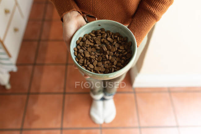 Close up of woman in kitchen, holding bowl of dog food. domestic lifestyle, enjoying leisure time at home. — Stock Photo