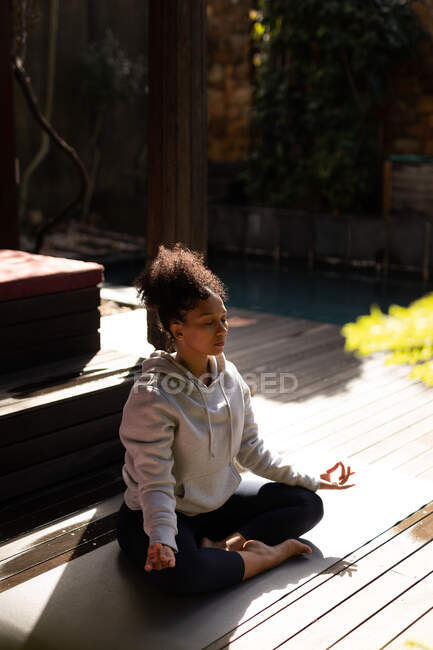 Mixed race woman practicing yoga on yoga mat and meditating. spending time off at home. — Stock Photo