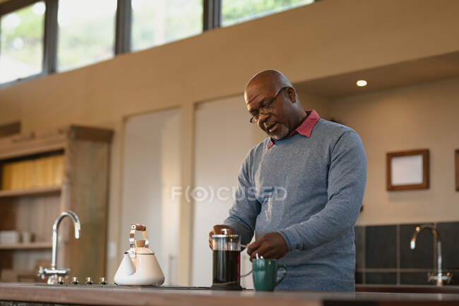 Uomo anziano afroamericano in cucina moderna che prepara un caffè. stile di vita di pensione, trascorrere del tempo da solo a casa. — Foto stock