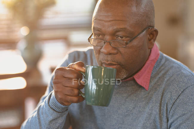 Homem americano africano sênior em picar a cozinha moderna beber um café. estilo de vida aposentadoria, passar o tempo sozinho em casa. — Fotografia de Stock