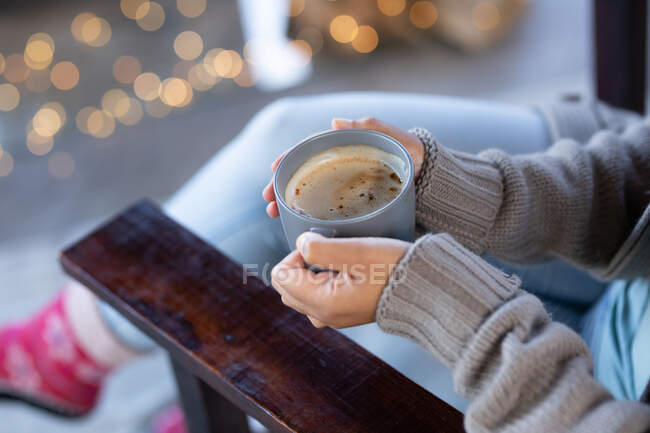 Жінка у вітальні сидить біля каміна, тримає кухоль і п'є каву. проводити вихідні вдома . . — стокове фото