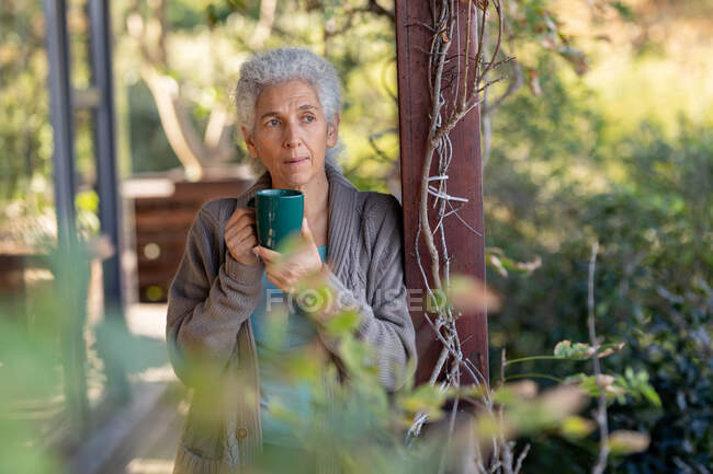 Relaxing senior caucasian woman on balcony standing and drinking coffee. retirement lifestyle, spending time alone at home. — Stock Photo