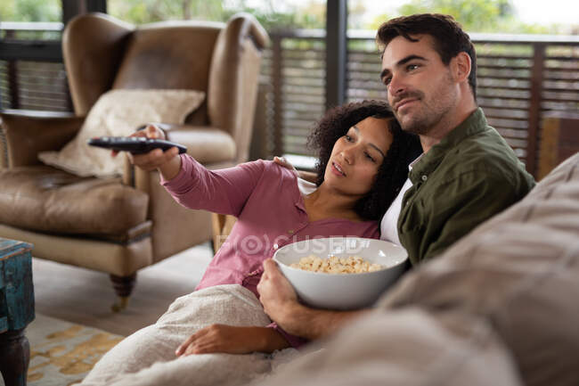 Счастливая пара, сидящая на диване в гостиной и смотрящая телевизор. проводить свободное время дома в современной квартире. — стоковое фото