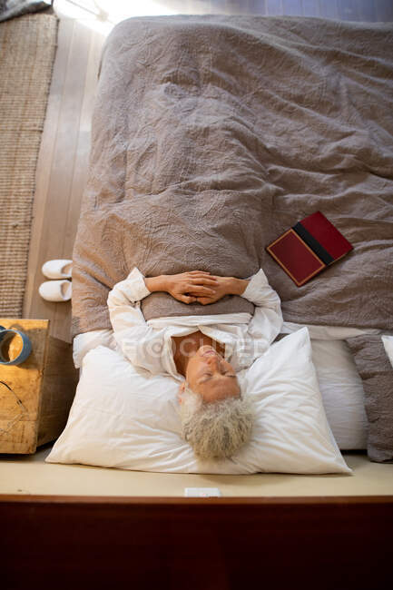 Ältere kaukasische Frau im Schlafzimmer, im Bett liegend und schlafend. Lebensstil im Ruhestand, Zeit allein zu Hause verbringen. — Stockfoto