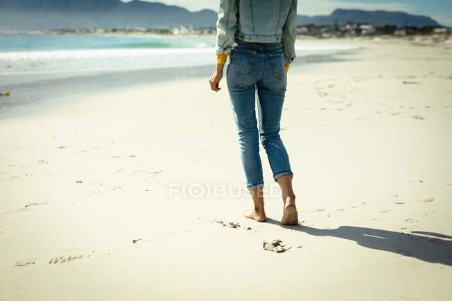 Mujer caminando en la playa en un día soleado. estilo de vida saludable, disfrutar del tiempo libre al aire libre. - foto de stock