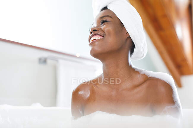 Rindo mulher afro-americana na casa de banho relaxante na banheira. estilo de vida doméstico, desfrutando de tempo de lazer auto-cuidado em casa. — Fotografia de Stock