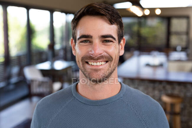 Portrait of happy caucasian man smiling and looking at camera. spending time off at home in modern apartment. — Stock Photo