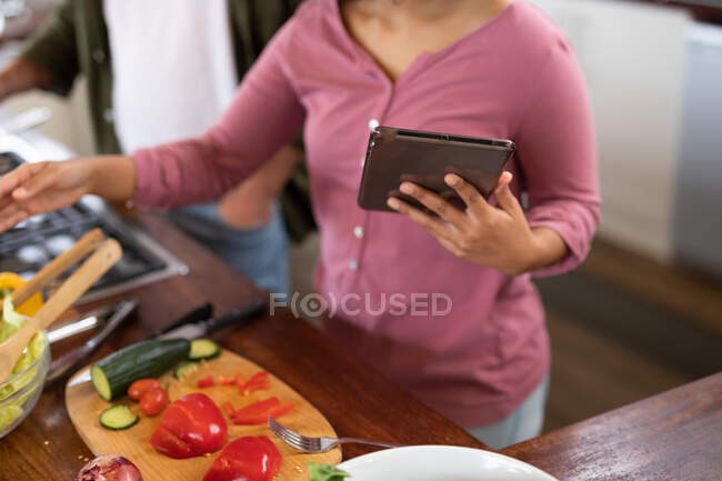Mulher na cozinha preparando alimentos usando computador tablet. passar o tempo fora em casa no apartamento moderno. — Fotografia de Stock