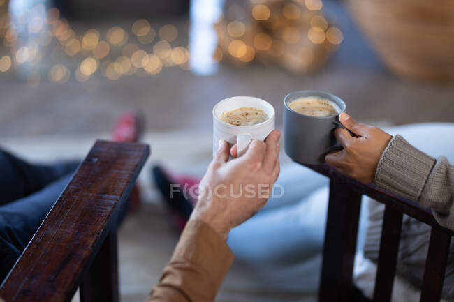 Casal na sala de estar segurando canecas e beber café. passar o tempo fora em casa. — Fotografia de Stock