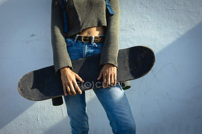 Section médiane de la femme tenant skateboard, style de vie, profiter du temps libre en plein air. — Photo de stock