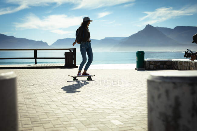 Mulher de raça mista skate no dia ensolarado à beira-mar. estilo de vida saudável, desfrutando de tempo de lazer ao ar livre. — Fotografia de Stock