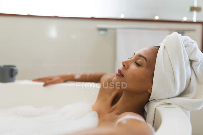 Donna razza mista in bagno con vasca da bagno, rilassante con gli occhi chiusi. stile di vita domestico, godendo di auto cura del tempo libero a casa. — Foto stock
