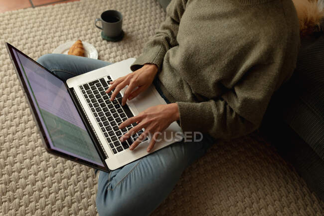 Жінка у вітальні, сидить на підлозі, працює з ноутбуком. домашній спосіб життя, віддалена робота з дому . — стокове фото