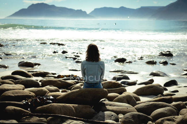 Mixed Race Frau sitzt an einem sonnigen Tag am Meer. gesunder Lebensstil, Freizeit im Freien genießen. — Stockfoto