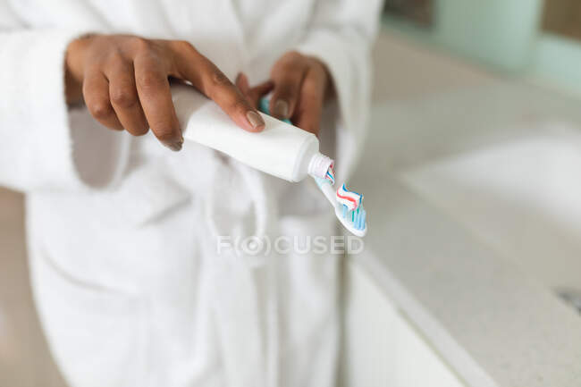Woman in bathroom holding toothpaste and toothbrush. domestic lifestyle, enjoying self care leisure time at home. — Stock Photo