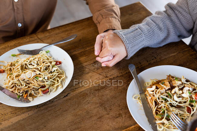 Close up of happy couple in living room eating dinner together holding hands. spending time off at home in modern apartment. — Stock Photo