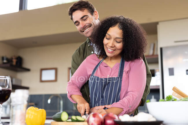 Счастливая разнообразная пара на кухне готовит еду вместе рубят овощи. проводить свободное время дома в современной квартире. — стоковое фото