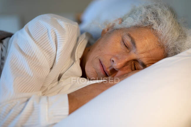 Mulher caucasiana sénior no quarto, deitada na cama e a dormir. estilo de vida aposentadoria, passar o tempo sozinho em casa. — Fotografia de Stock