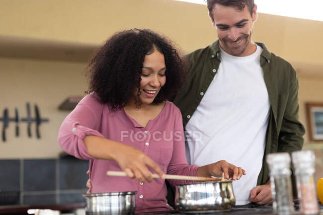 Feliz casal diversificado na cozinha preparando comida juntos conversando e sorrindo. passar o tempo fora em casa no apartamento moderno. — Fotografia de Stock