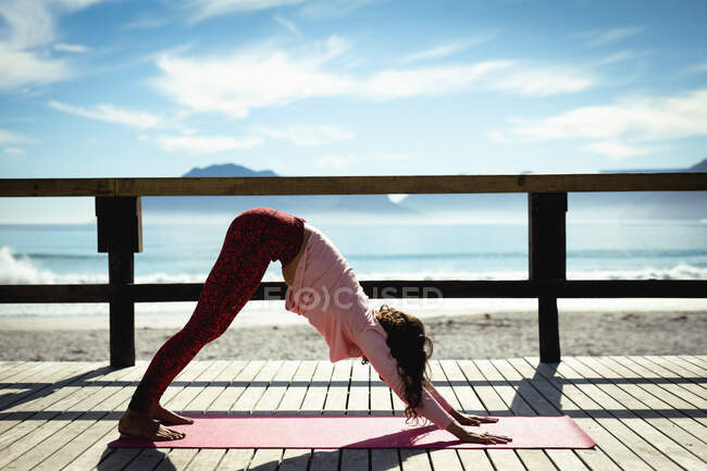 Mulher de raça mista praticando ioga no dia ensolarado à beira-mar. estilo de vida saudável, desfrutando de tempo de lazer ao ar livre. — Fotografia de Stock