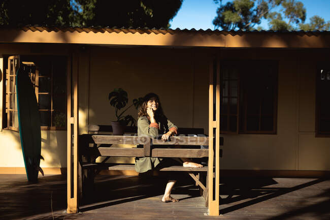 Смешанная расовая женщина сидит и улыбается в солнечном саду. здоровый образ жизни, наслаждаясь отдыхом дома. — стоковое фото