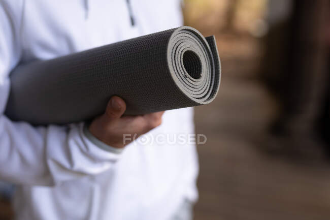 Primo piano di uomo che tiene tappetino yoga prima di praticare yoga. trascorrere del tempo libero a casa. — Foto stock