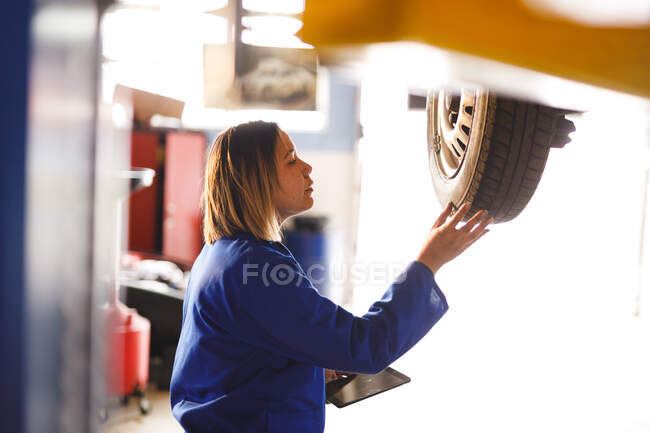 Misto gara femminile meccanico di auto indossando tuta, ispezionare auto. proprietario indipendente presso il garage di assistenza auto. — Foto stock