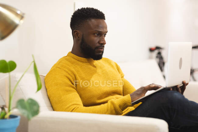 Nachdenkliche afrikanisch-amerikanische Männer, die kreativ auf dem Sofa in der Lounge am Arbeitsplatz sitzen und arbeiten. unabhängige kreative Geschäftsleute, die in einem modernen Büro arbeiten. — Stockfoto