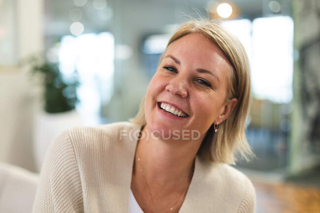 Sonriente mujer caucásica negocio creativo mirando a la cámara en el lugar de trabajo cafetería. empresarios creativos independientes que trabajan en una oficina moderna. - foto de stock