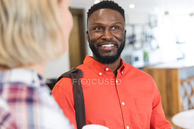 Smiling diverse female and male colleagues standing at workplace lounge area and talking. independent creative business people at a modern office. — Stock Photo