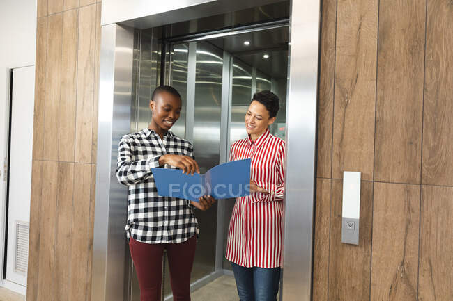 Happy diverse female creative colleagues holding notes and talking in workplace lounge area. independent creative business people at a modern office. — Stock Photo