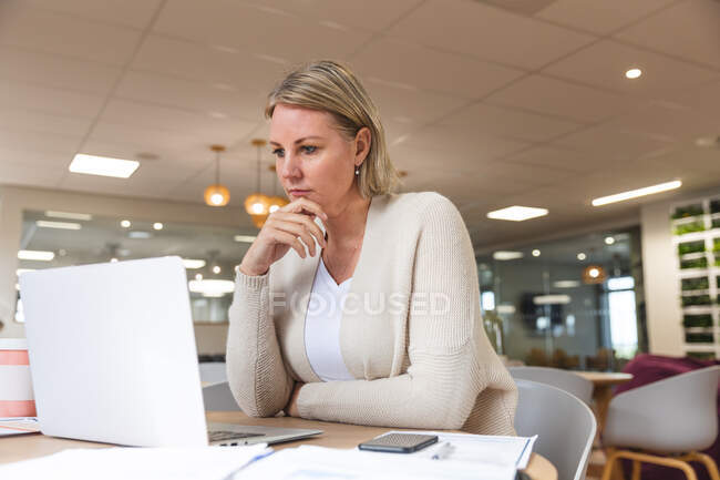 Entreprise féminine caucasienne réfléchie créative en utilisant un ordinateur portable à la cafétéria du lieu de travail. entrepreneurs créatifs indépendants travaillant dans un bureau moderne. — Photo de stock