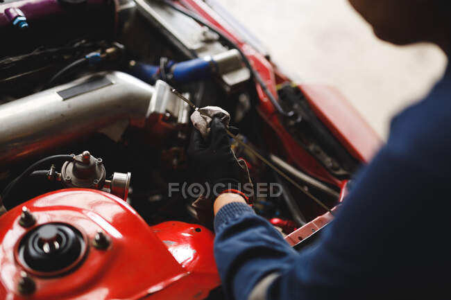 Primo piano di mani di meccanico di auto femminile che indossa tuta intera, controllando il livello dell'olio. proprietario indipendente presso il garage di assistenza auto. — Foto stock