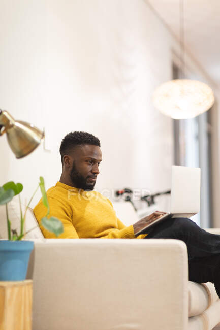 Thoughtful african american male business creative sitting on sofa in workplace lounge and working. independent creative business people working at a modern office. — Stock Photo