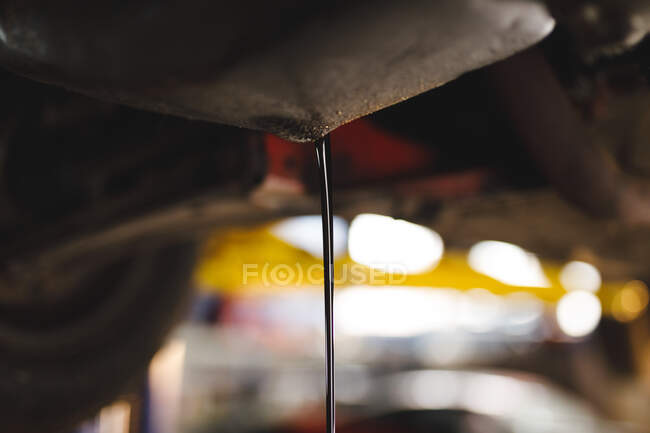 Close up of oil pouring out of car. independent business owner at car servicing garage. — Stock Photo